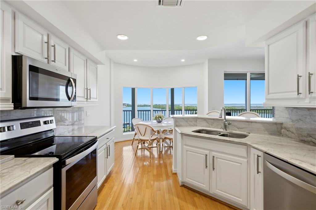 The gourmet-inspired kitchen features 36-inch cabinetry, quartz countertops, stainless steel appliances and a dedicated breakfast area framed by a stunning bay window with floor-to-ceiling glass, inviting abundant natural light and serene views.
