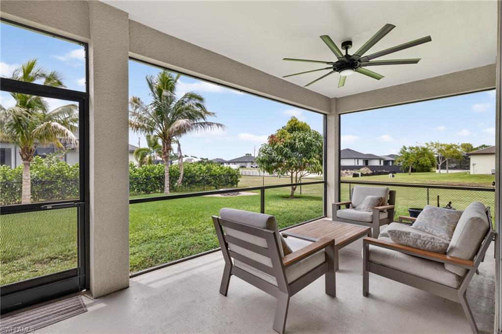 Screened patio featuring a ceiling fan, concrete flooring, and a expansive grassy area