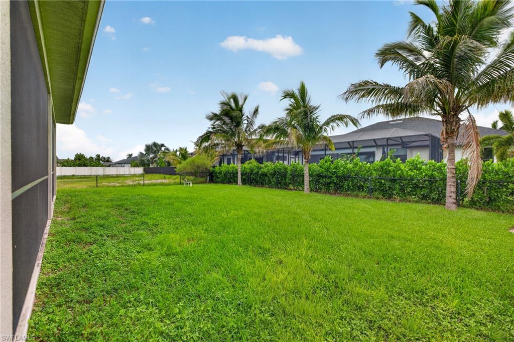 Expansive green lawn with mature palm trees and established hedges