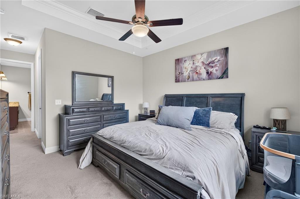 Tray ceiling with crown molding, ceiling fan with integrated lighting, recessed lighting, carpet flooring, and light-toned wall paint
