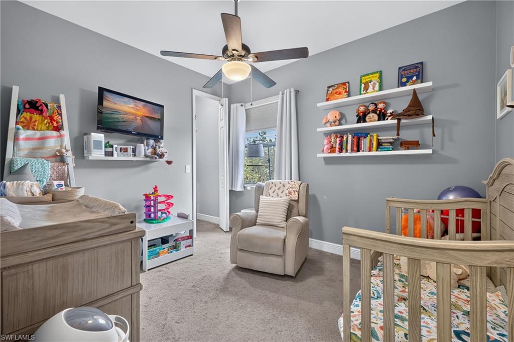 Neutral gray wall paint with white trim, ceiling fan with integrated lighting, recessed window with white blinds, and wall-mounted shelving