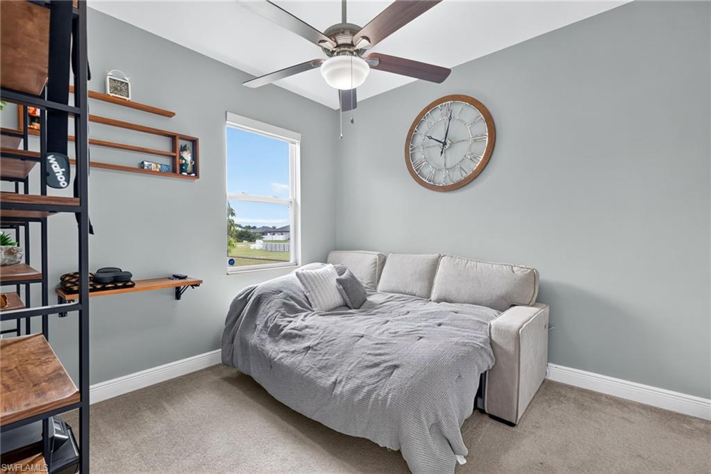 Wall-mounted shelving, built-in desk, and a ceiling fan with integrated lighting