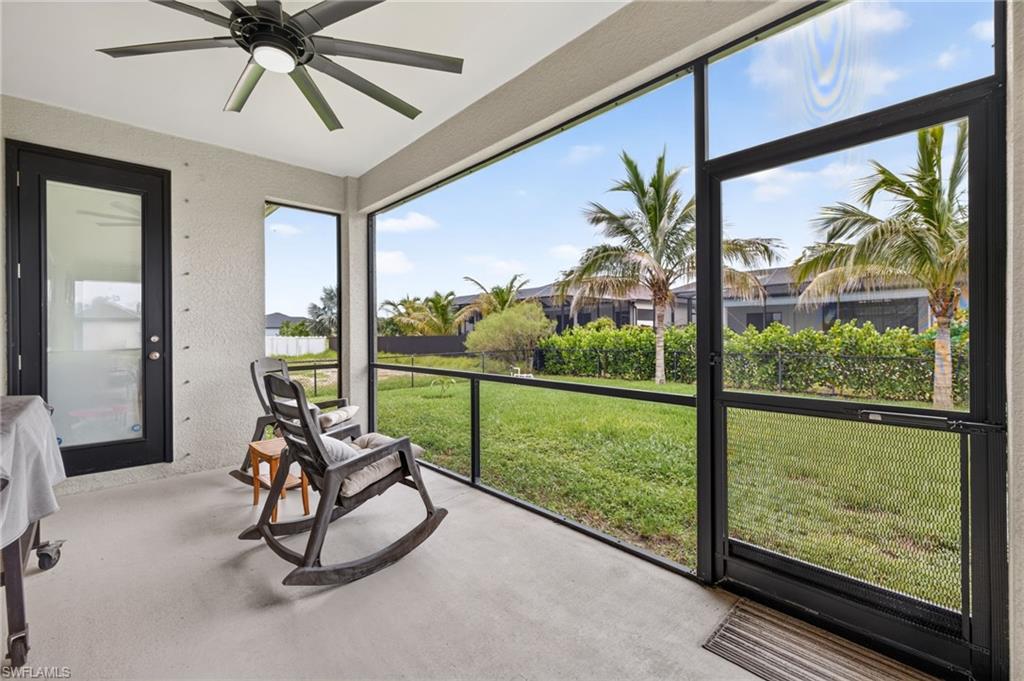 Screened outdoor living space with a ceiling fan, concrete flooring, and a glass-paneled exterior door