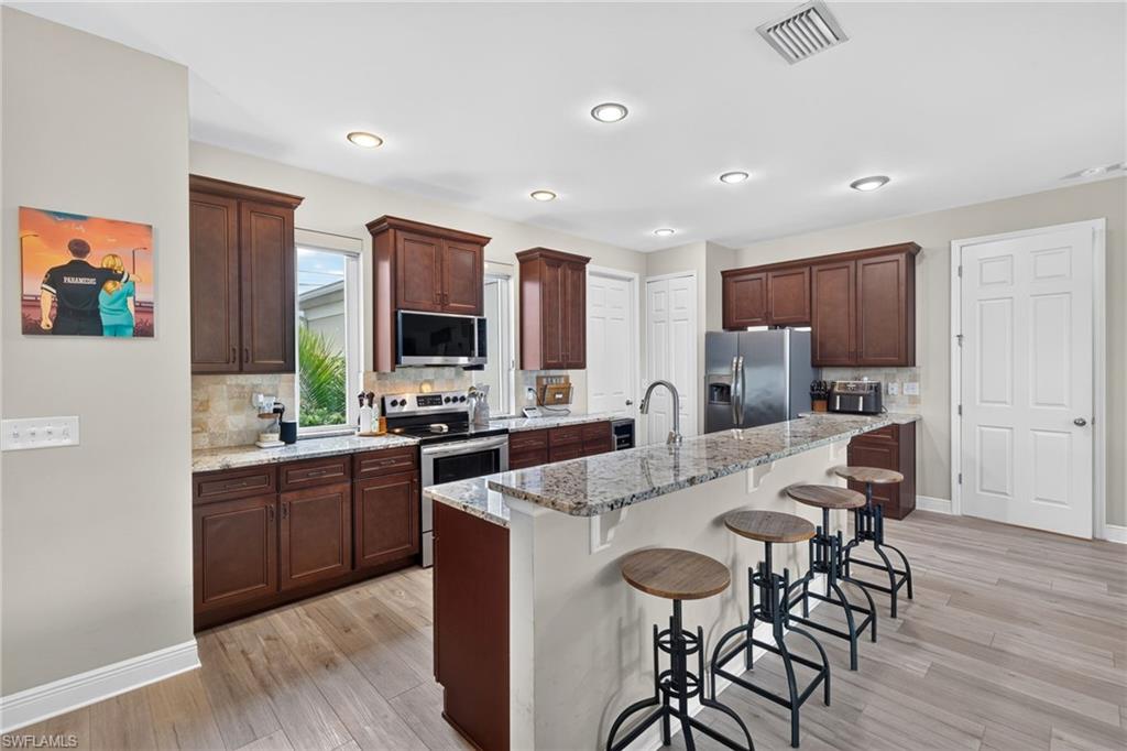 Kitchen featuring wood-finish flooring, dark wood cabinetry, granite countertops, and recessed lighting