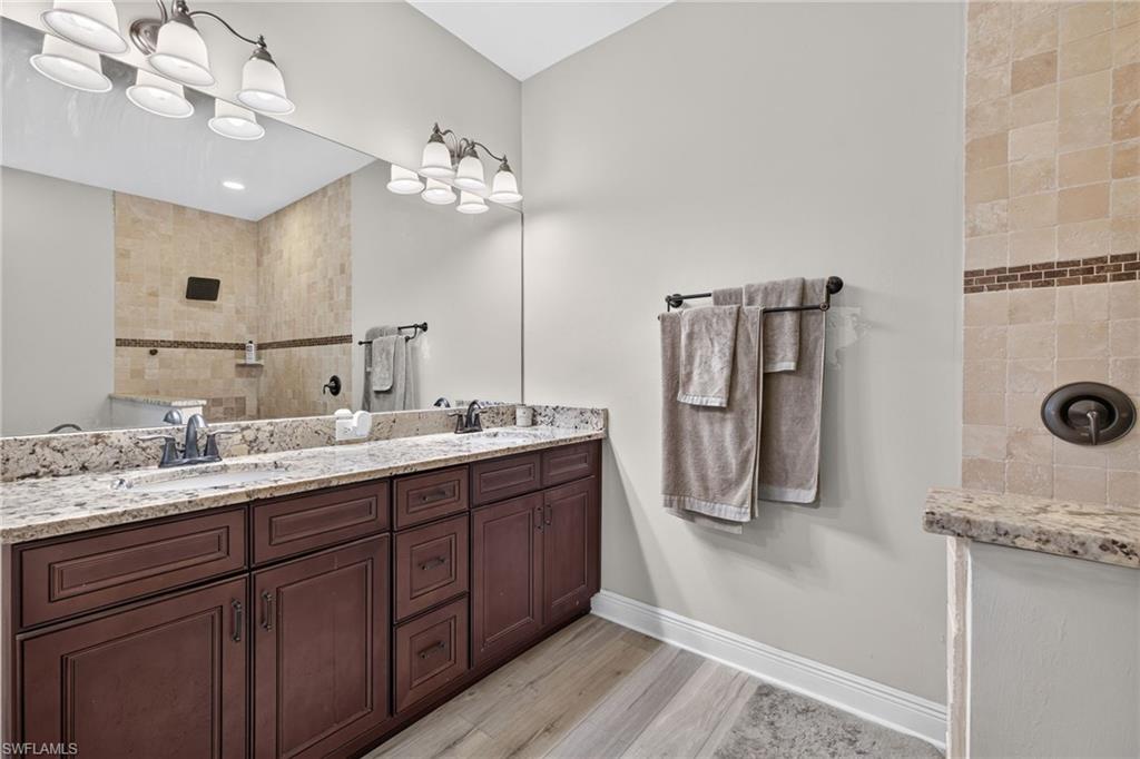 Dual vanity with granite countertops, wood-finish cabinetry, and brushed nickel fixtures