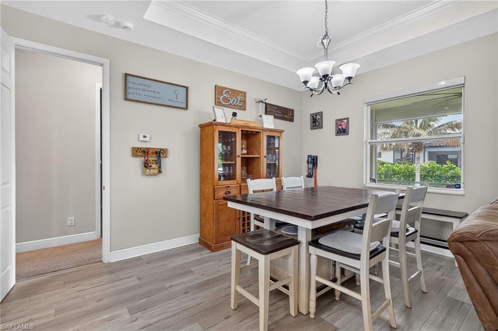 Tray ceiling with crown molding, wood-finish flooring, and recessed lighting
