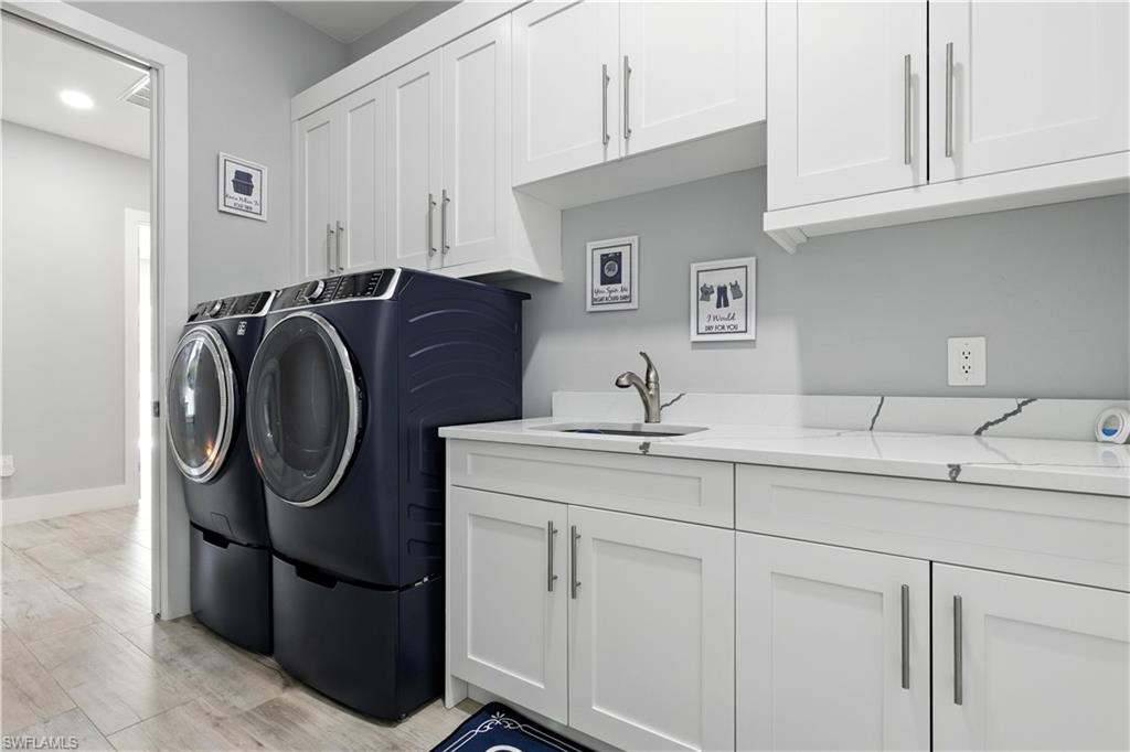 Washroom with washer and dryer, cabinet space, light wood-style floors, and recessed lighting
