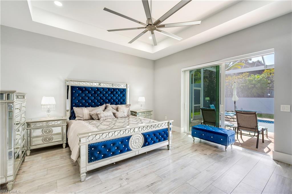 Bedroom featuring a tray ceiling, access to outside, wood tiled floors, recessed lighting, and ceiling fan
