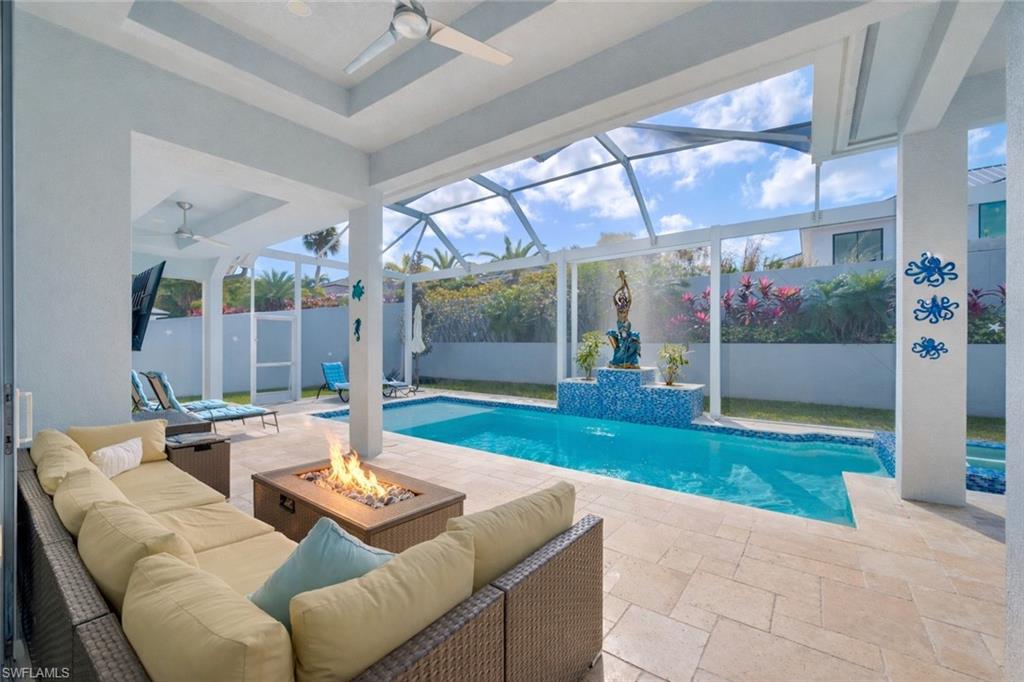 View of swimming pool with a sunroom, a patio, glass enclosure, and an outdoor living space with a fire pit