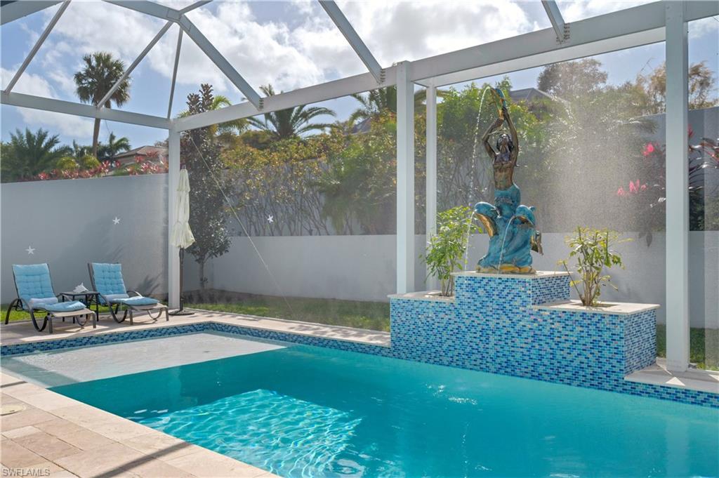 Swimming pool featuring glass enclosure, a patio, and a sunroom
