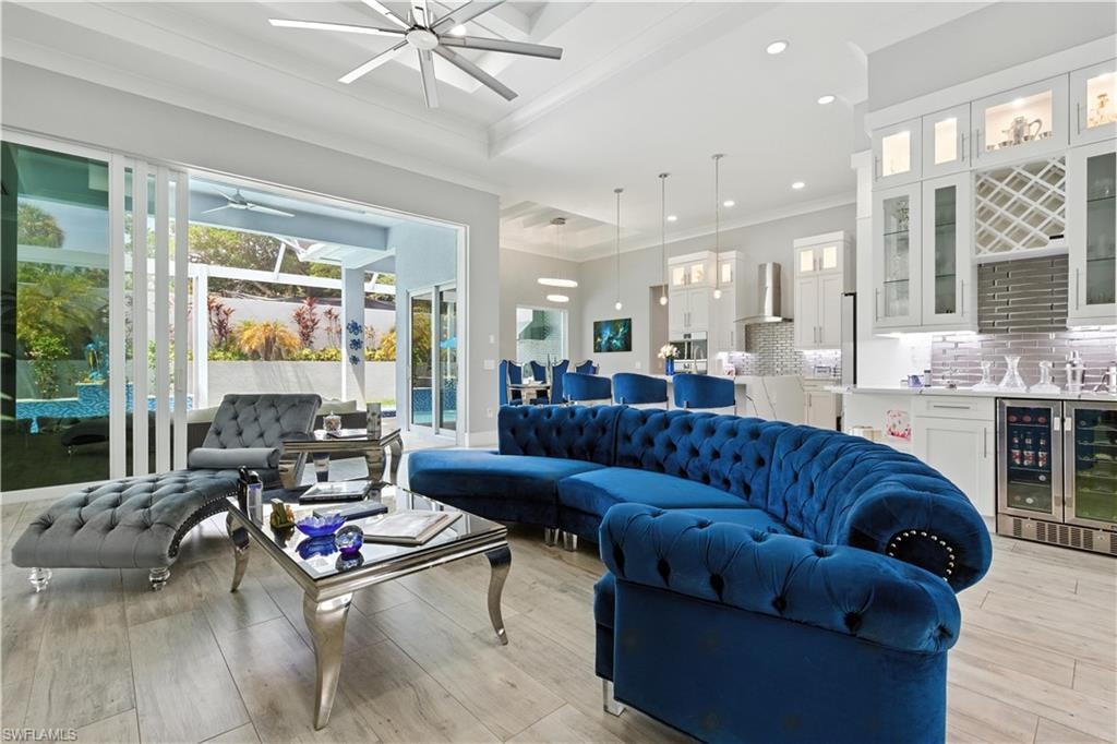 Living area with wine cooler, a ceiling fan, ornamental molding, light wood-style flooring, and recessed lighting