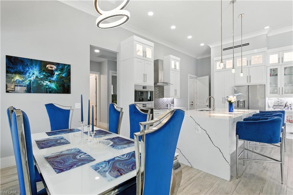 Dining space with ornamental molding, light wood-style flooring, and recessed lighting