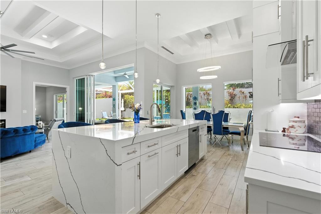 Kitchen with open floor plan, ceiling fan, crown molding, beam ceiling, and a high ceiling