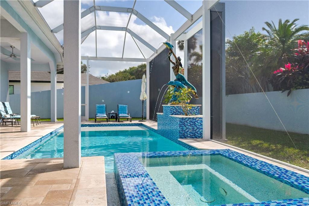 View of swimming pool featuring a patio area, a sunroom, glass enclosure, and a pool with connected hot tub