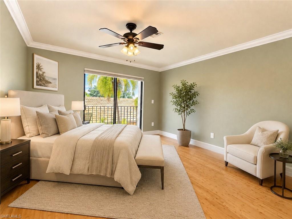 Wood-finish flooring with crown molding, ceiling fan, and sliding glass doors leading to a balcony with metal railings