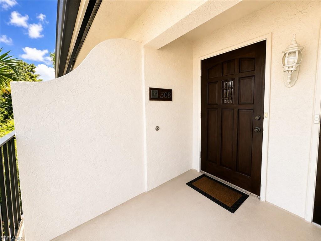 Dark wood-paneled entry door with decorative grille, flanked by a white exterior sconce