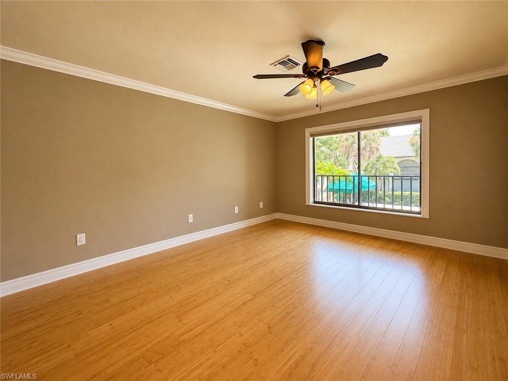 Spacious primary bedroom featuring a neutral color palette, hardwood flooring, and abundant natural light from sliding glass doors opening to a private balcony