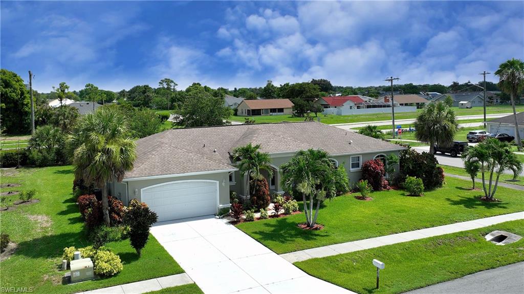 Single-story residence with an attached garage, paved driveway, and mature landscaping