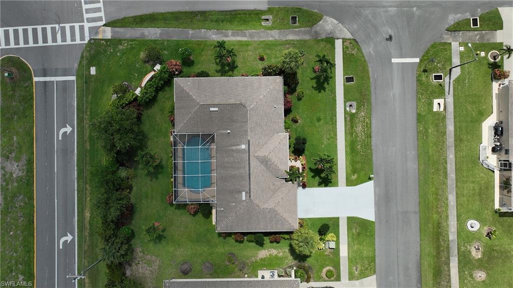 Gable roof with a screened enclosure pool, surrounded by a manicured lawn and mature landscaping