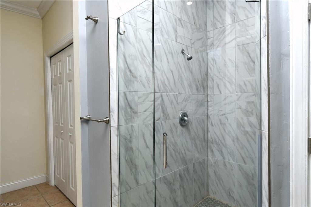 Spa-inspired shower enclosure featuring frameless glass doors, dual showerheads, and elegant marble-look tile walls with coordinating floor surfaces