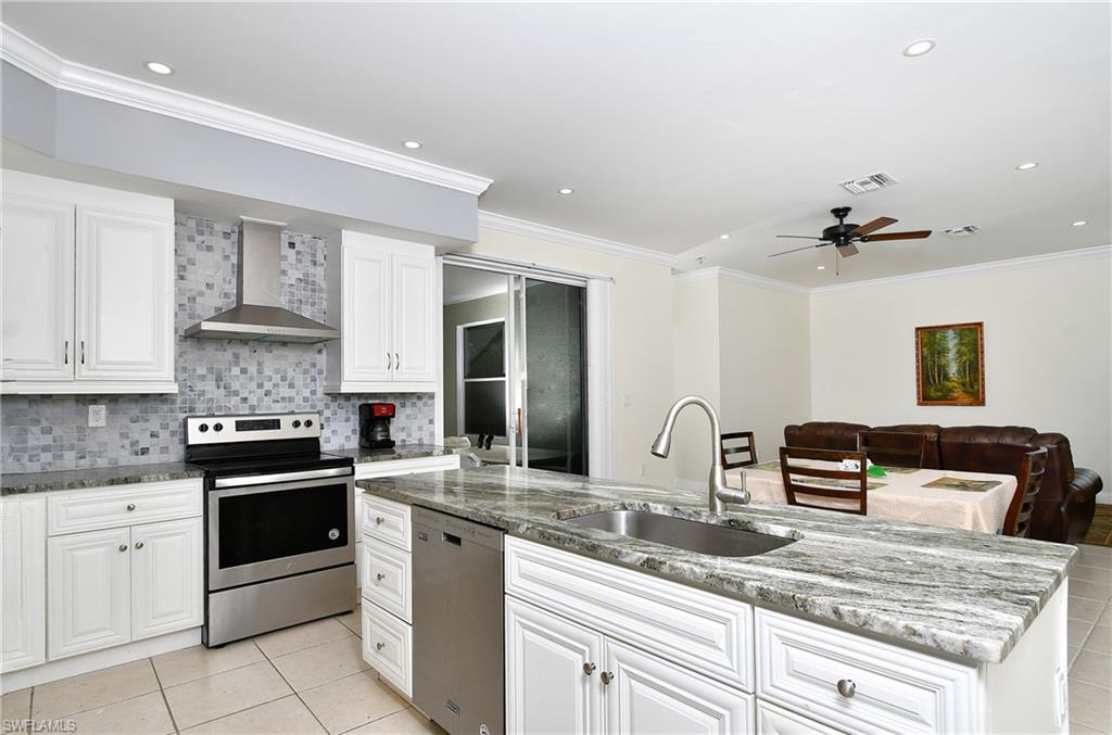 Kitchen featuring white cabinetry, stone-finish countertops, stainless steel appliances, and a tiled backsplash