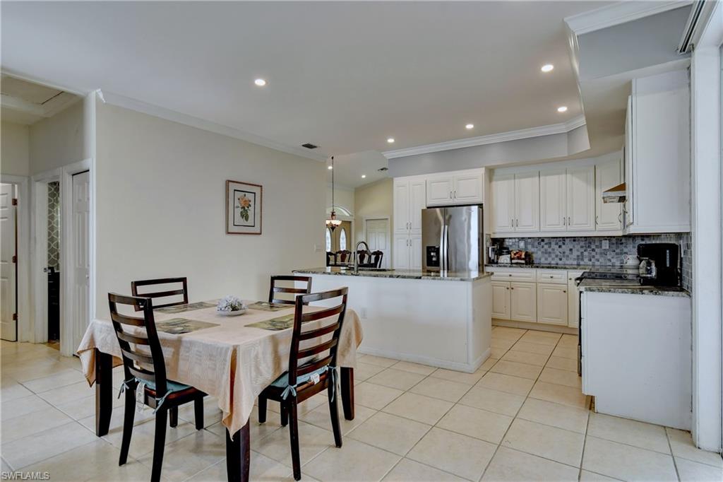 Kitchen featuring white cabinetry, stainless steel refrigerator, mosaic tile backsplash, and recessed lighting