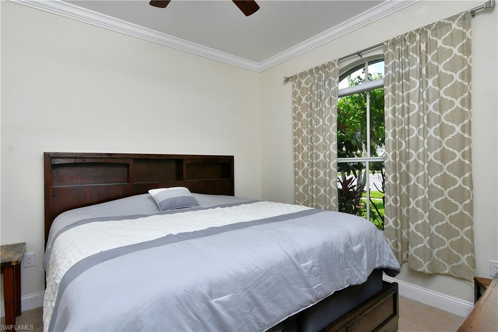 Arch-top window with exterior greenery, crown molding, and ceiling fan