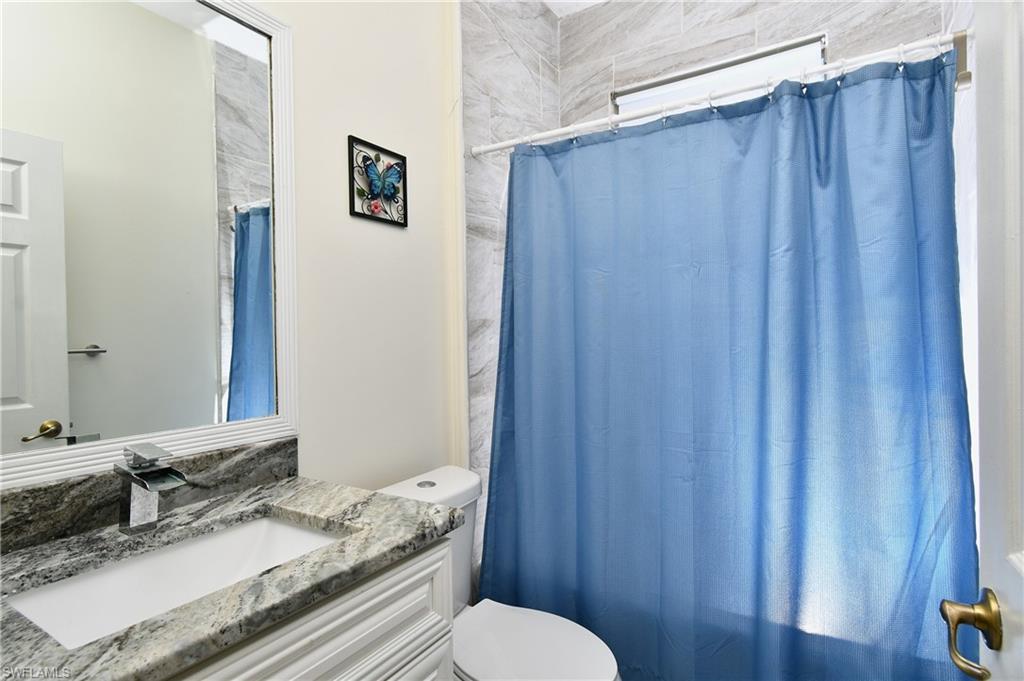 Vanity with stone countertop, undermount sink, and chrome faucet