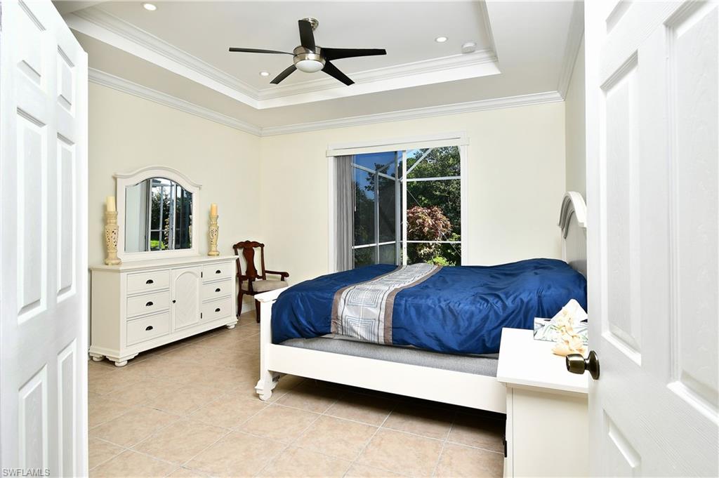 Spacious primary bedroom showcasing a coffered ceiling with ceiling fan, neutral wall finishes, and abundant natural light from sliding glass doors