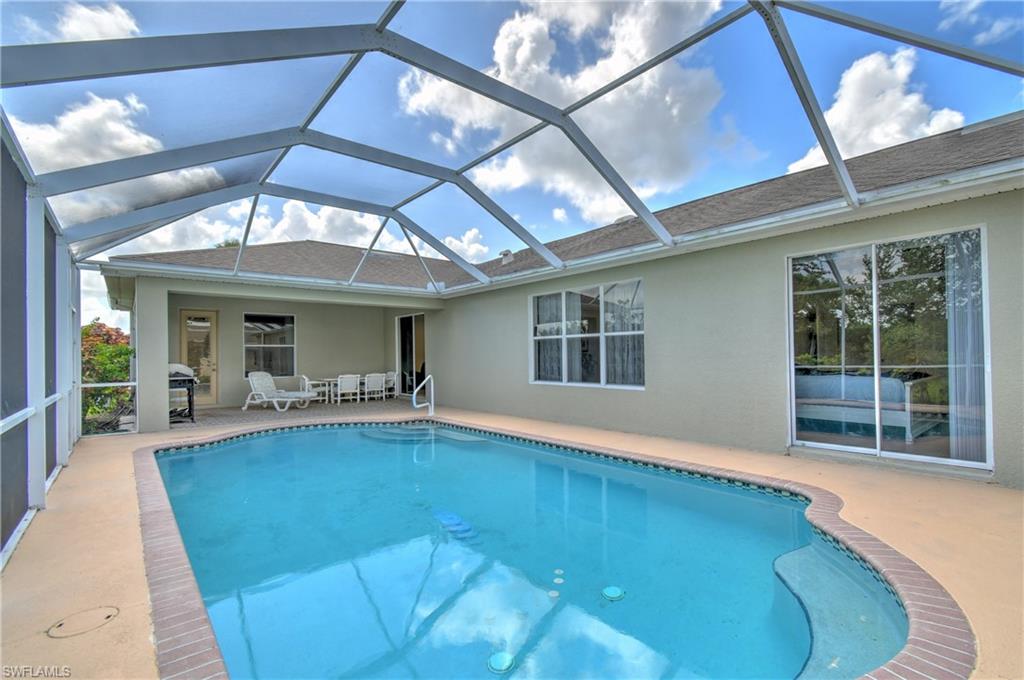 Screened enclosure over a swimming pool with a brick coping, an adjacent covered patio, and large sliding glass doors