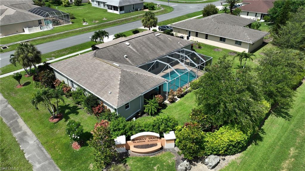 L-shaped single-story residence with a screened pool enclosure, lush landscaping, and a well-maintained lawn