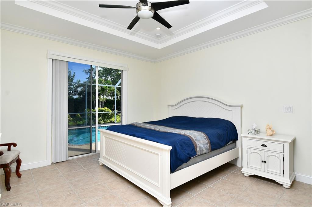 Tray ceiling with crown molding and ceiling fan, ceramic tile flooring, and sliding glass doors with direct pool access