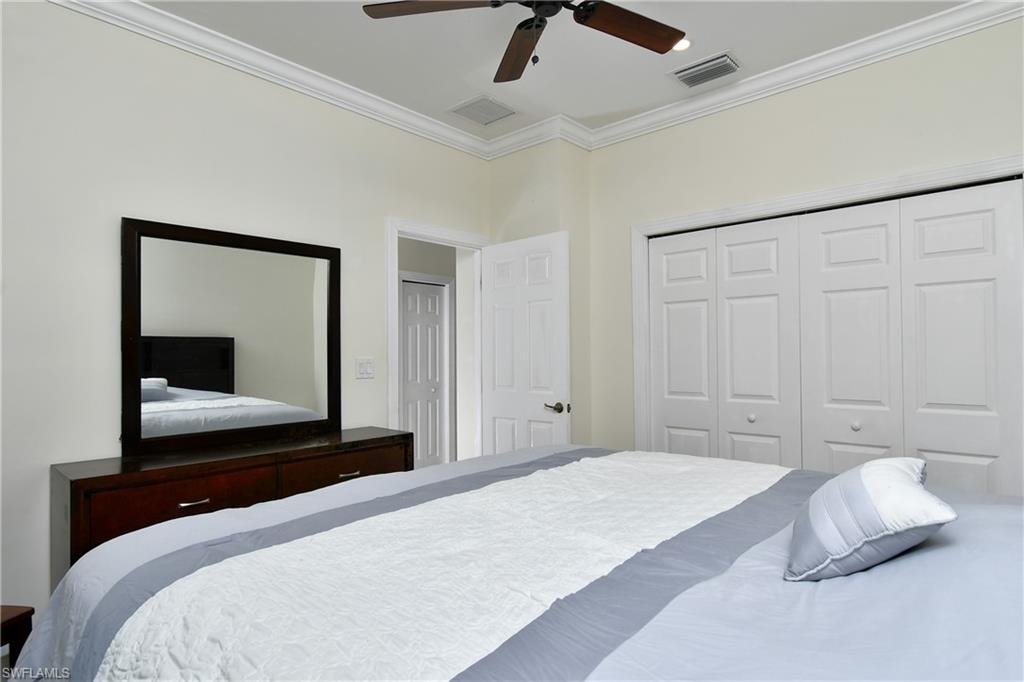 Ceiling fan with integrated lighting, crown molding, white paneled bifold closet doors, and a paneled interior door