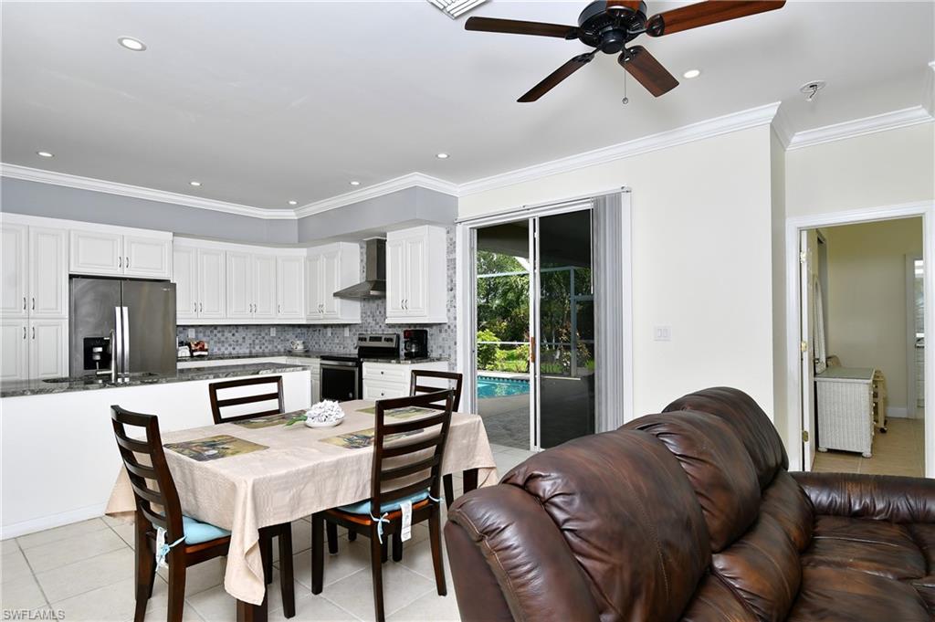 Recessed lighting, wood-finish ceiling fan, white cabinetry with dark hardware, stainless steel appliances, and sliding glass doors