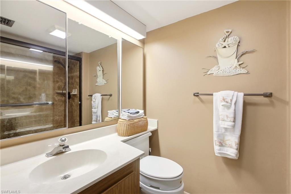 Bathroom featuring a vanity with an integrated sink, a large mirrored medicine cabinet, and a glass-enclosed shower with a tiled surround