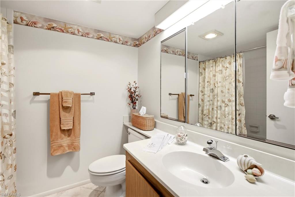 Bathroom featuring a single vanity with a white countertop, an integrated sink, and a chrome faucet