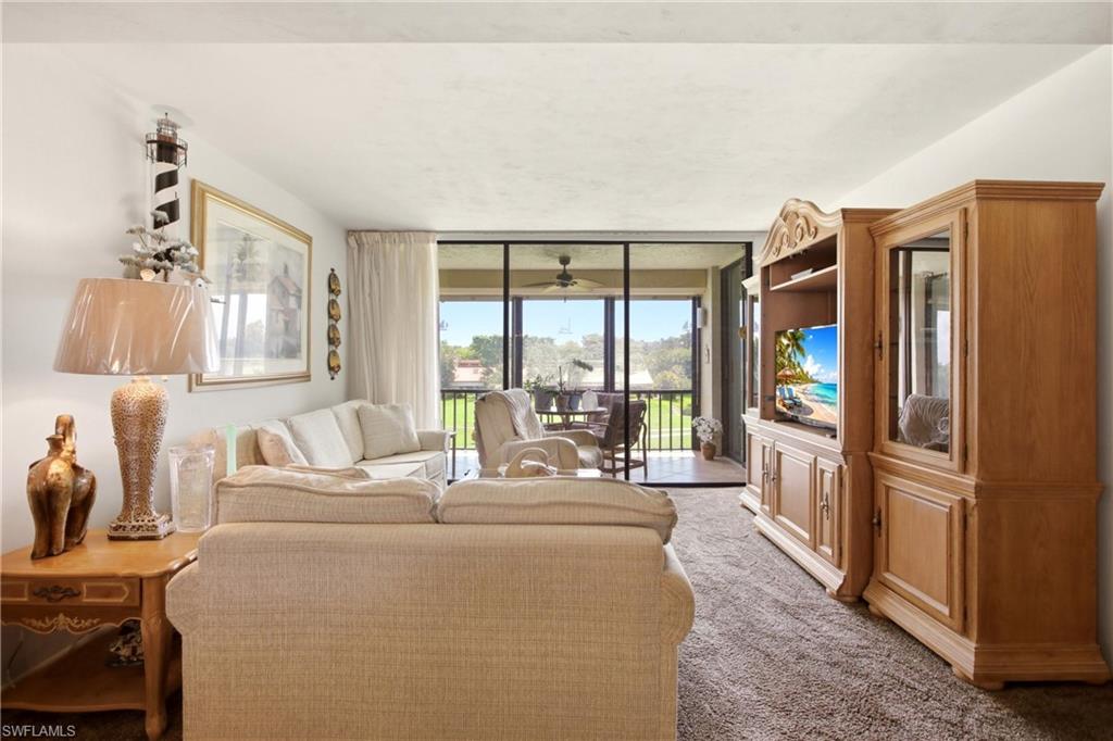 Living area featuring plush carpeting, a built-in entertainment center with display cabinets, and access to an outdoor screened-in balcony