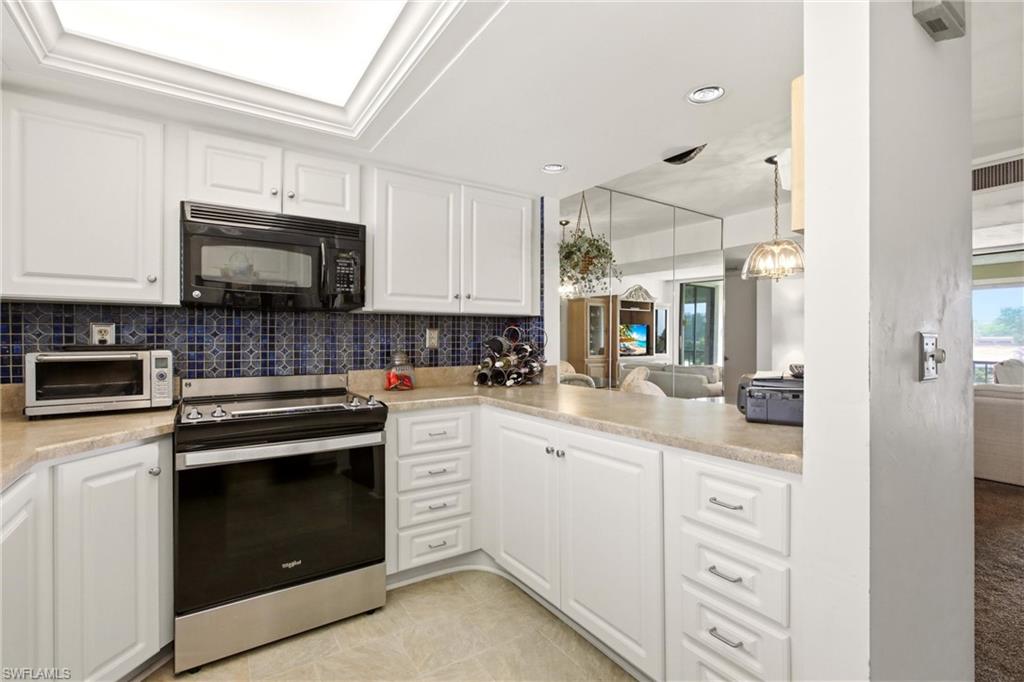 Kitchen featuring white cabinetry, a blue mosaic tile backsplash, and light-toned countertops