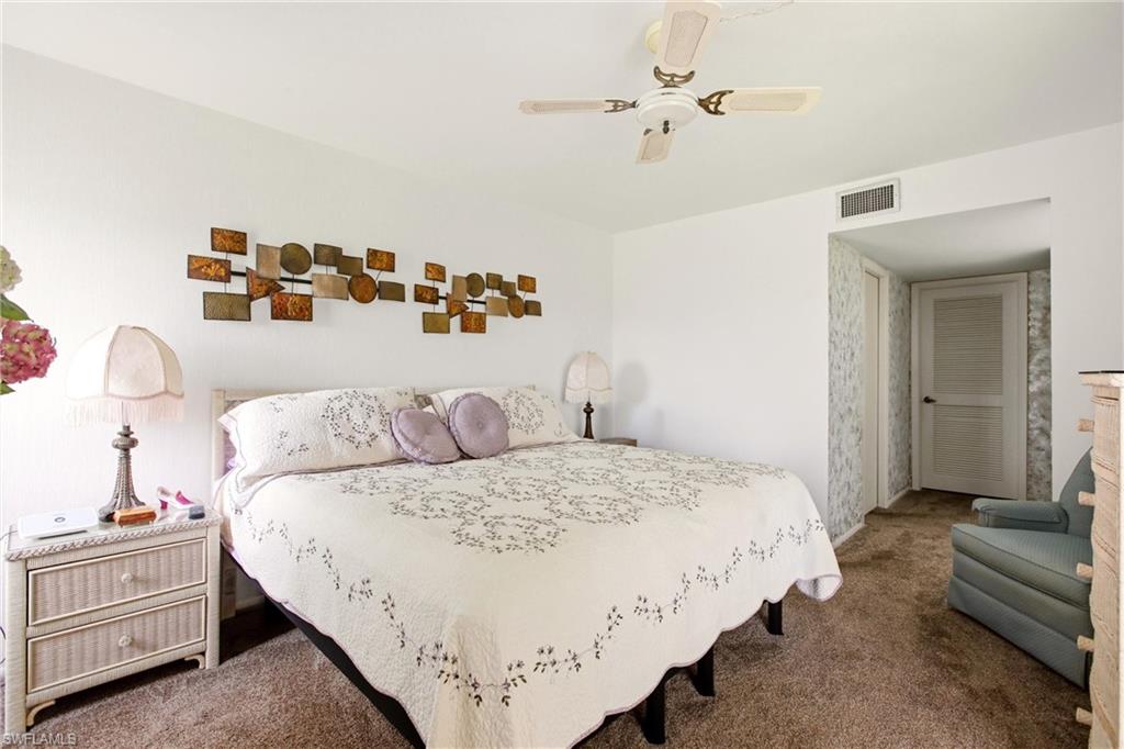 Spacious room featuring neutral carpeting, white walls, a ceiling fan, and a louvered door