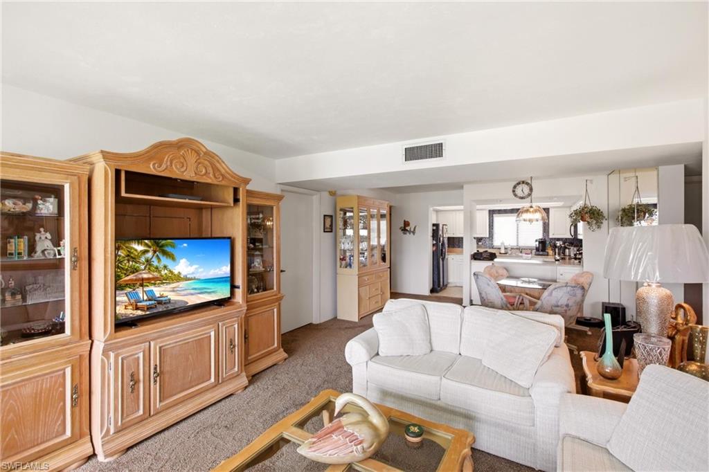 Open-concept living space featuring neutral carpeting and a smooth ceiling