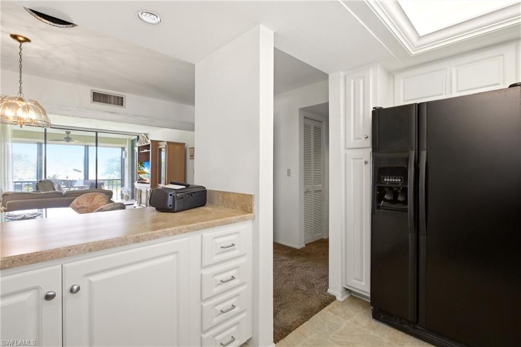 Kitchen pass-through featuring light-toned countertops and white cabinetry