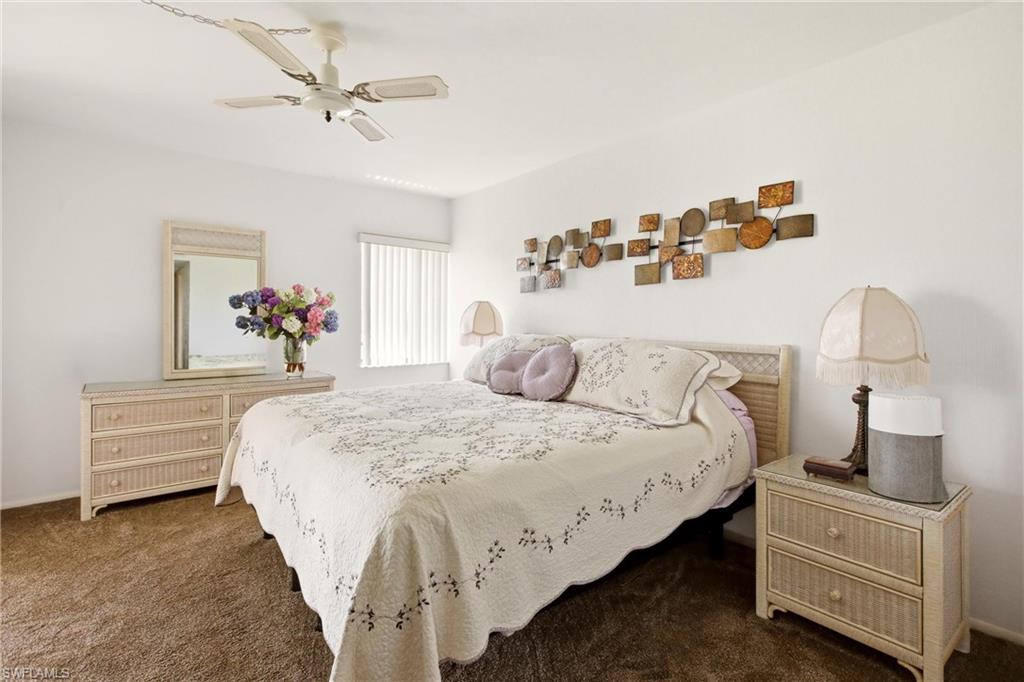 Spacious room featuring white walls, brown carpeting, and a ceiling fan with integrated lighting
