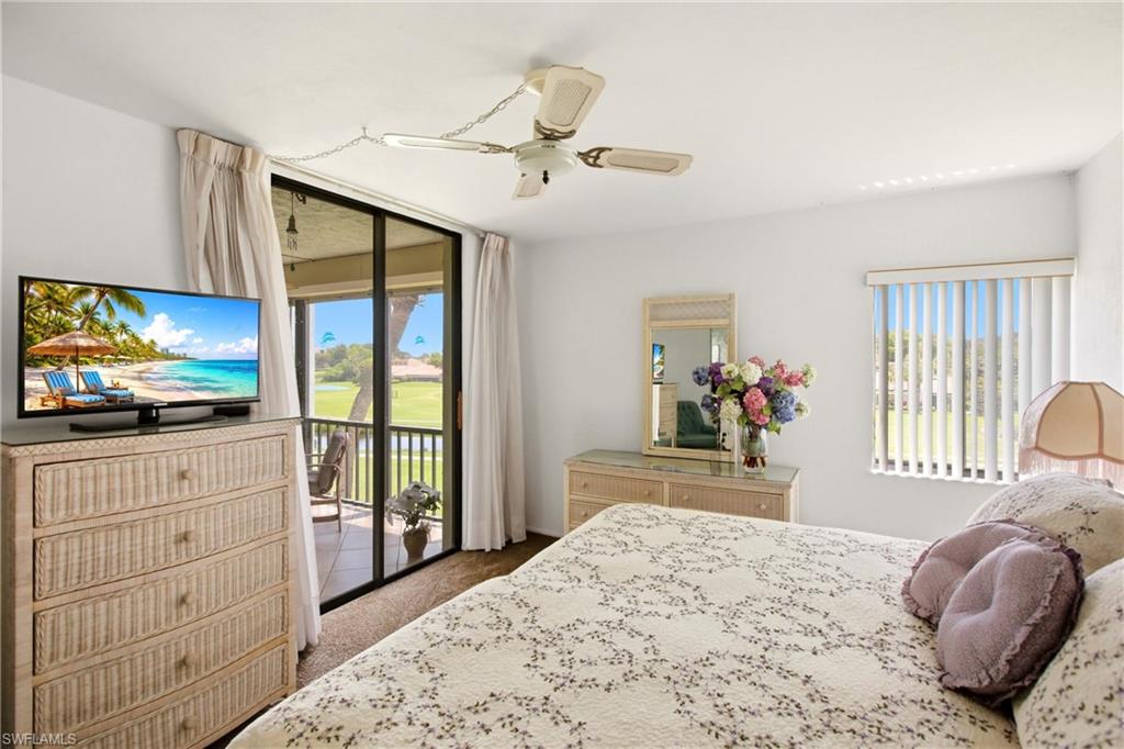 Interior room featuring a sliding glass door to an outdoor balcony, overhead ceiling fan with lighting, white walls, and wood-finish flooring