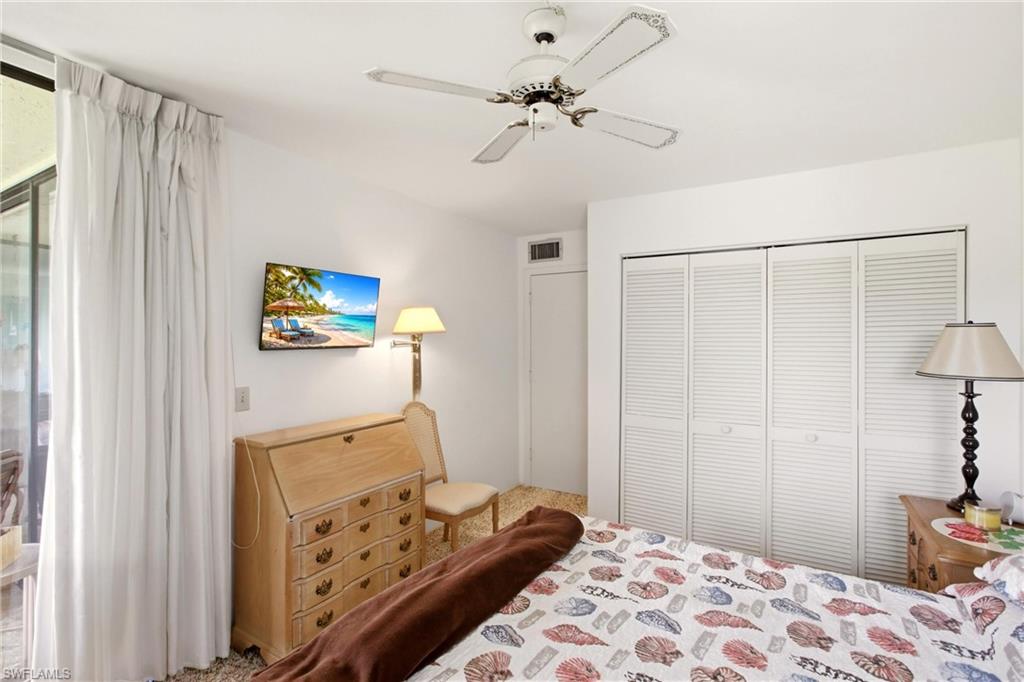White louvered bi-fold closet doors, ceiling fan, and wall-mounted television