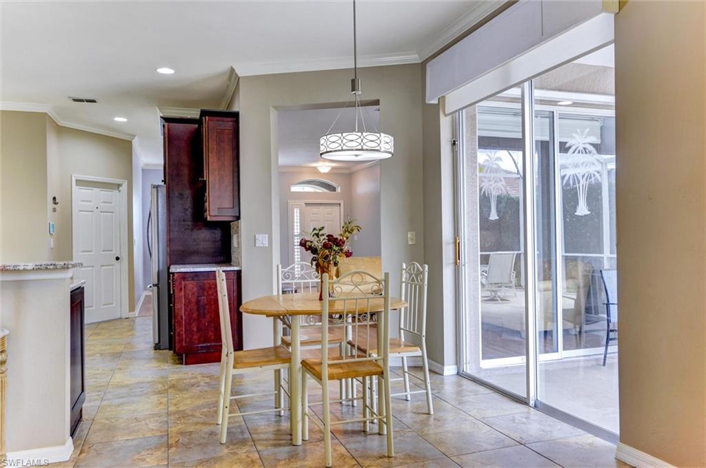 Tiled flooring in a neutral tone, dark wood-finish cabinetry, recessed lighting, and a decorative pendant light fixture