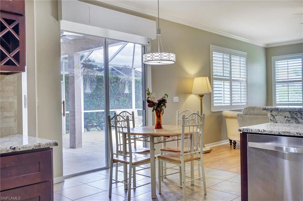 Sliding glass doors, tiled flooring, wood-finish flooring, white plantation shutters, and granite countertops