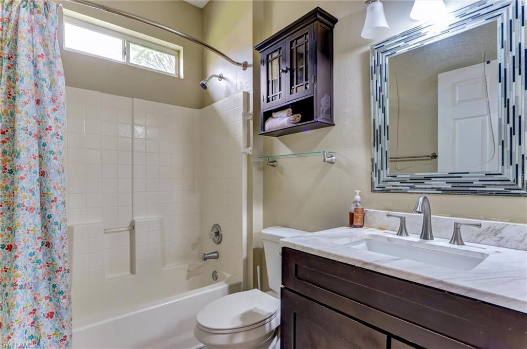Vanity with a light-toned countertop, dark wood-finish cabinetry, and a framed mirror