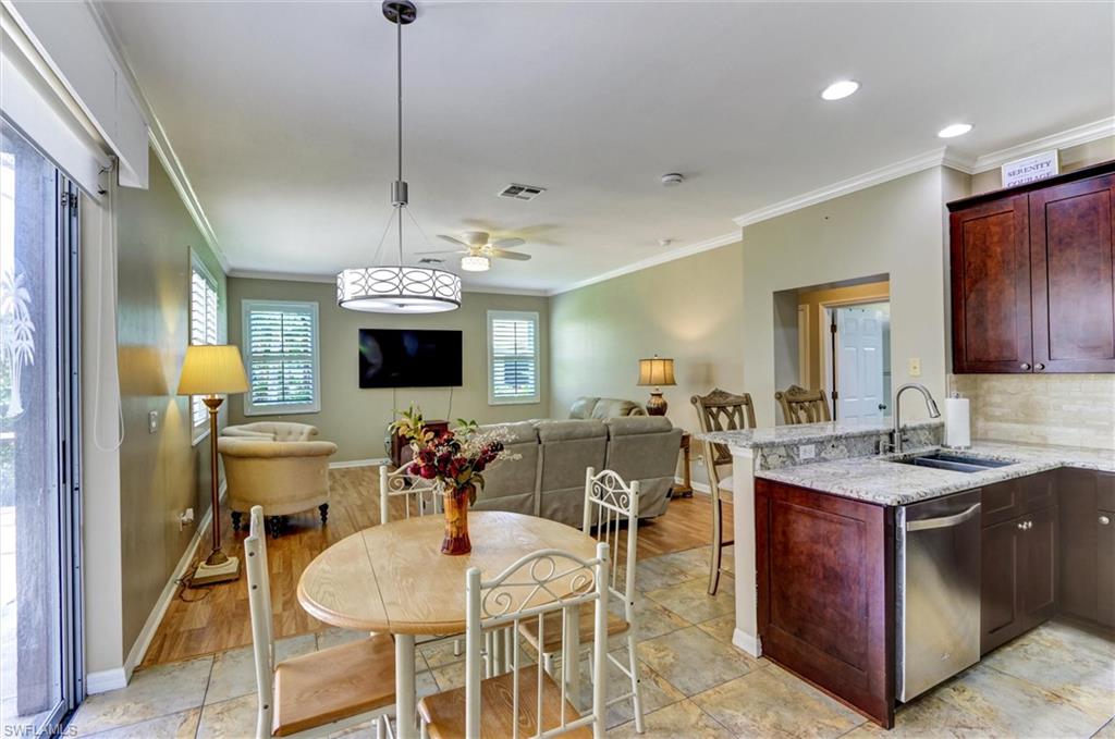 Open-concept living space featuring wood-finish flooring, a kitchen with granite countertops, dark wood cabinetry, and stainless steel appliances