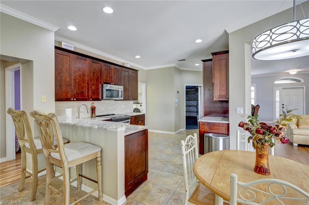 Kitchen featuring wood cabinetry, stainless steel appliances, and a breakfast bar with stone countertops