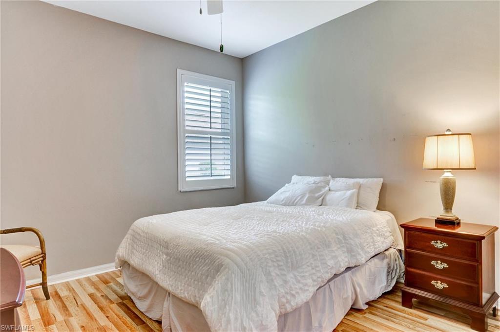 Hardwood flooring, window with white plantation shutters, neutral wall color, white trim, ceiling fan